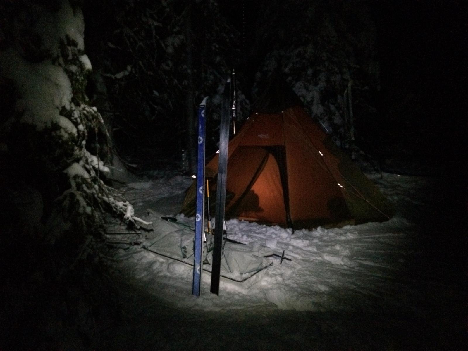 Kotateltta valaistuna talviyössä