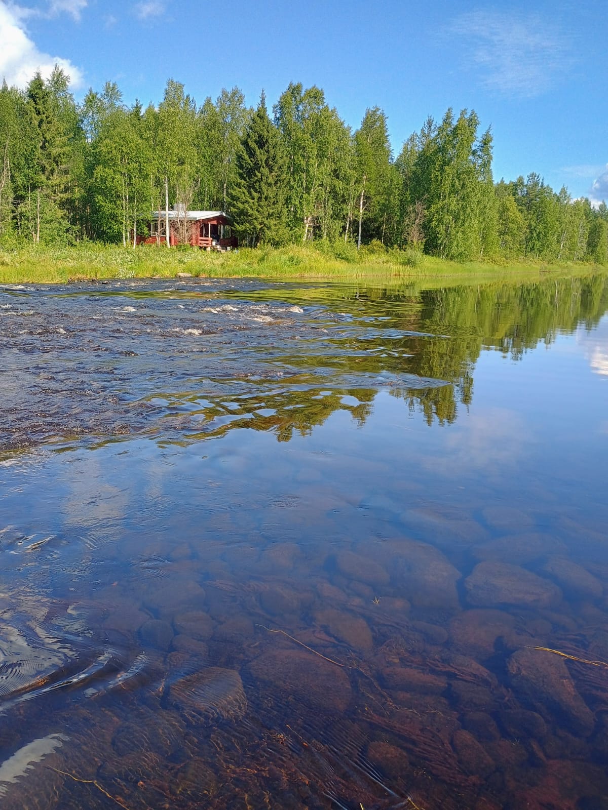 Erämökki kuohuvan kosken rannalla Suomussalmella