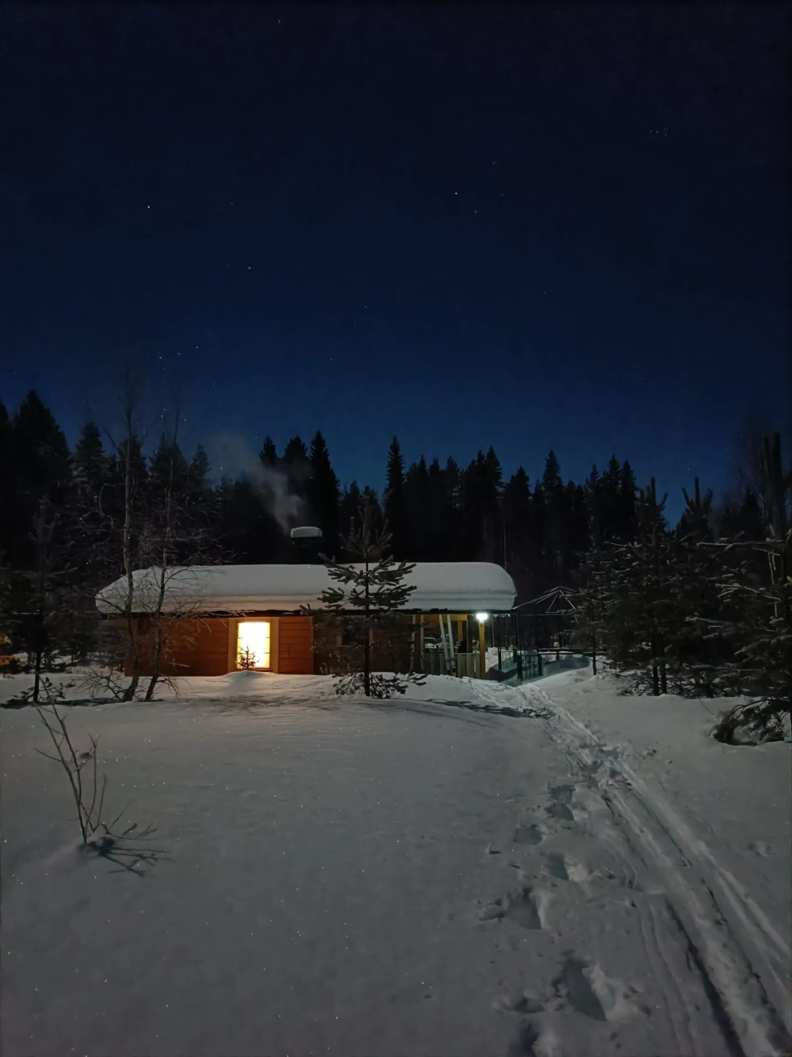 Erämökki talvisessa yössä tähtitaivaan alla