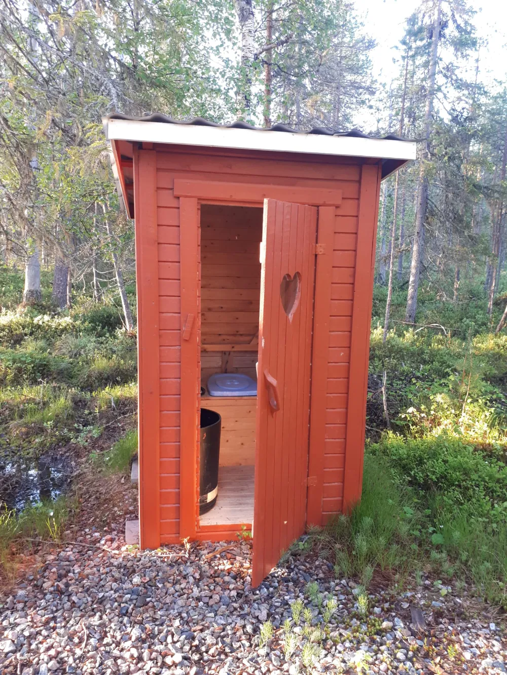 Punainen ulkohuussi metsässä